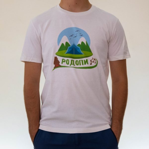 Man wearing a white unisex T-shirt featuring an illustration of the Rhodope Mountains, a tent, a wolf howling, and the text "Родопи" in Cyrillic with musical notes.