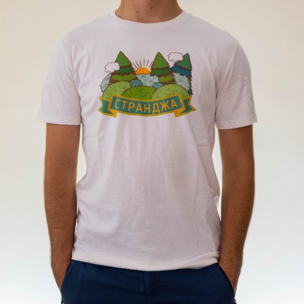 Person wearing a white unisex T-shirt featuring a colorful mountain and forest illustration with the word "Странджа" in Cyrillic.