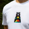byala-teniska-s-mechka-cherna Close-up of a white unisex T-shirt featuring a "Boho" bear design with a colorful mountain landscape, sun, and tribal-inspired elements.