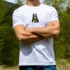 byala-teniska-s-mechka-planinar Man wearing a white unisex T-shirt with a small "Boho" bear design on the chest, featuring a colorful mountain landscape and a rising sun.