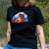 Woman wearing a black unisex T-shirt with a "Bears" design featuring a bear guarding a tent by a campfire in a colorful forest.