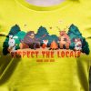 Close-up of a yellow T-shirt with a "Respect the Locals" print, featuring forest animals gathered around a campfire.