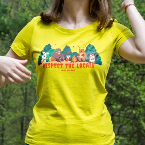 damska-teniska-gorchica-zhylta-respect-the-locals Woman wearing a yellow T-shirt with a "Respect the Locals" print featuring forest animals gathered around a campfire.