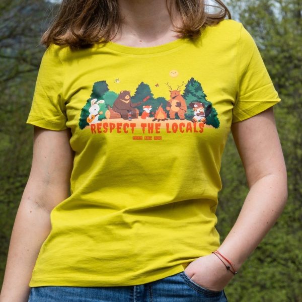 Woman wearing a yellow T-shirt with a "Respect the Locals" print featuring forest animals sitting around a campfire.
