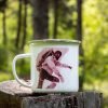 kanche-za-planina-kenche-metalno (5) White enamel camping mug featuring a vintage alpinist photograph, placed on a wooden stump with a lush green forest in the background.