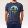 myzhka-teniska-siva-za-planina-pirin Man wearing a dark gray unisex T-shirt with a "Pirin" mountain design, featuring sharp peaks, green hills, and a deer silhouette.