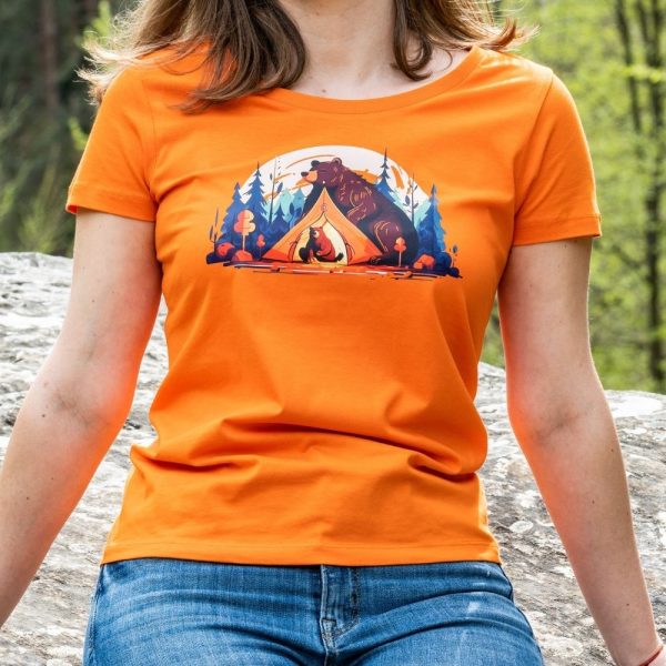 Woman wearing an orange fitted T-shirt with a camping bear design, featuring a mother bear and cub around a tent and campfire.
