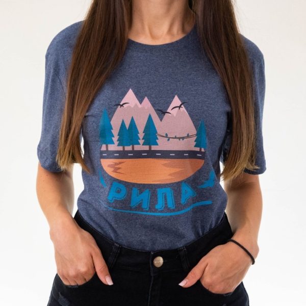 teniska-damska-siva-za-planinarka-rila Woman wearing a dark gray unisex T-shirt featuring an illustration of Rila mountain, pine trees, a river, and the text "Рила" in Cyrillic.