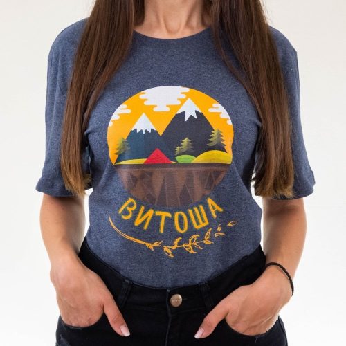 teniska-damska-siva-za-planinarka-vitosha Woman wearing a dark gray unisex T-shirt featuring an illustration of Vitosha mountain, pine trees, a small house, and the text "Витоша" in Cyrillic.