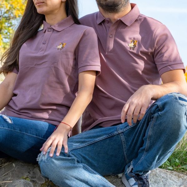 Man and woman wearing matching mauve polo T-shirts with an embroidered bear design, sitting outdoors on a sunny day.