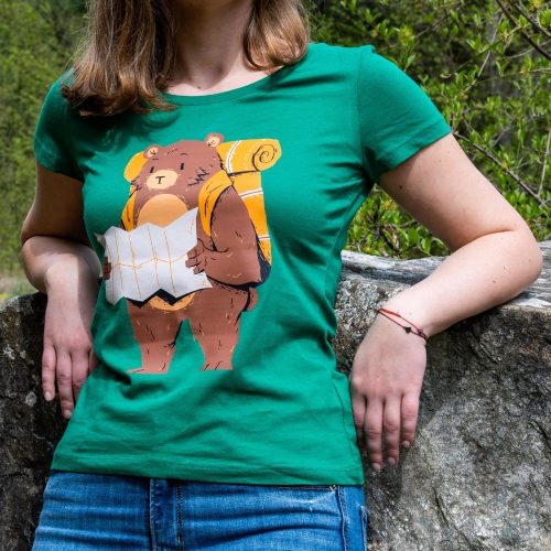zelena-damska-teniska-mechka-s-ranitsa Woman wearing a green T-shirt featuring a design of a bear with a backpack holding a map, symbolizing adventure and exploration.