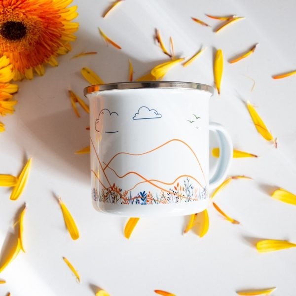 Podarak-za-momiche-zhena-planinarka (6) White enamel camping mug featuring a minimalist mountain landscape with orange contour lines, clouds, birds, and wildflowers, surrounded by yellow flower petals.