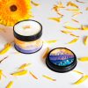 Podarak-za-momiche-zhena-planinarka (8) Natural soy wax candle with a wooden wick in a black metal tin, featuring a mountain sunset design, surrounded by yellow flower petals.