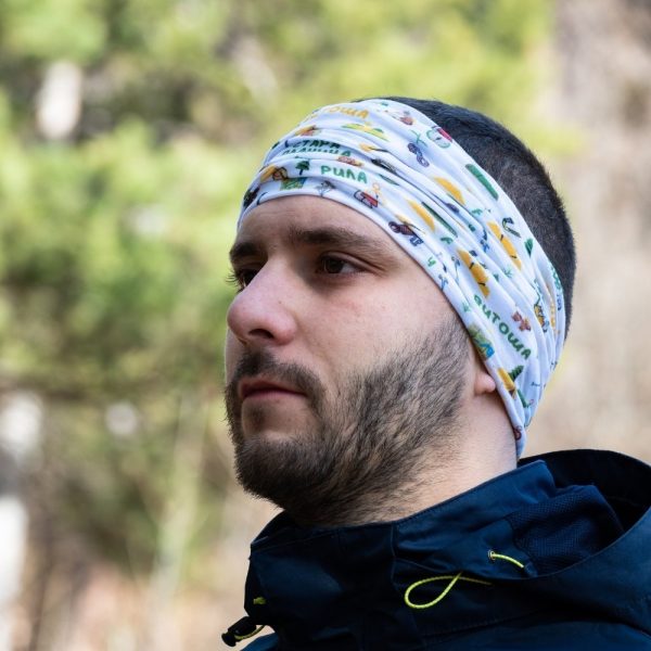 bandana-za-planina-lenta A white multifunctional buff with Bulgarian mountain names and outdoor-themed illustrations, worn as a headband by a man in a navy blue jacket.