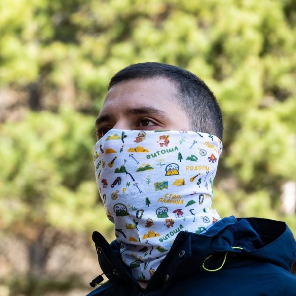 bandana-za-planina-maska Man wearing a multifunctional white buff around his neck and lower face, featuring Bulgarian mountain names and outdoor-themed illustrations.