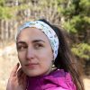 bandana-za-planina-zhena Woman wearing a white multifunctional buff as a headband, decorated with Bulgarian mountain names and hiking-themed illustrations.