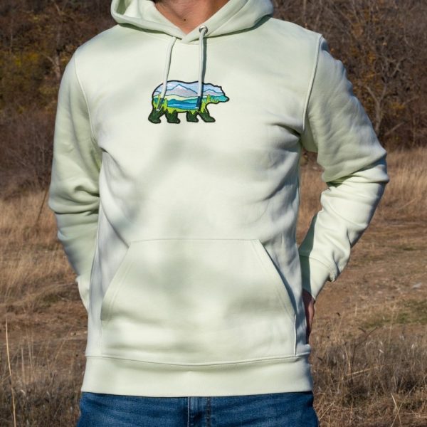 Light green hoodie with an embroidered bear featuring a scenic mountain landscape.
