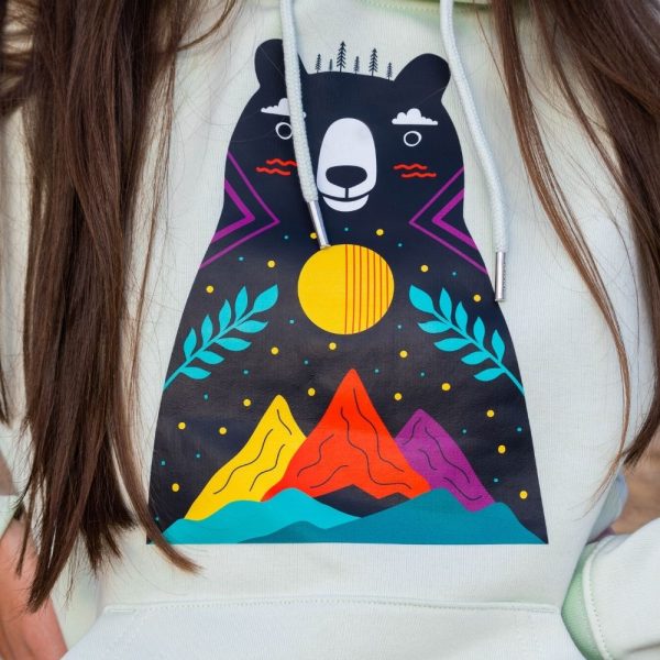 hoodie-sweatshirt-zelen-cvyat-s-mechka Close-up of a colorful bear and mountain print on a light green hoodie.