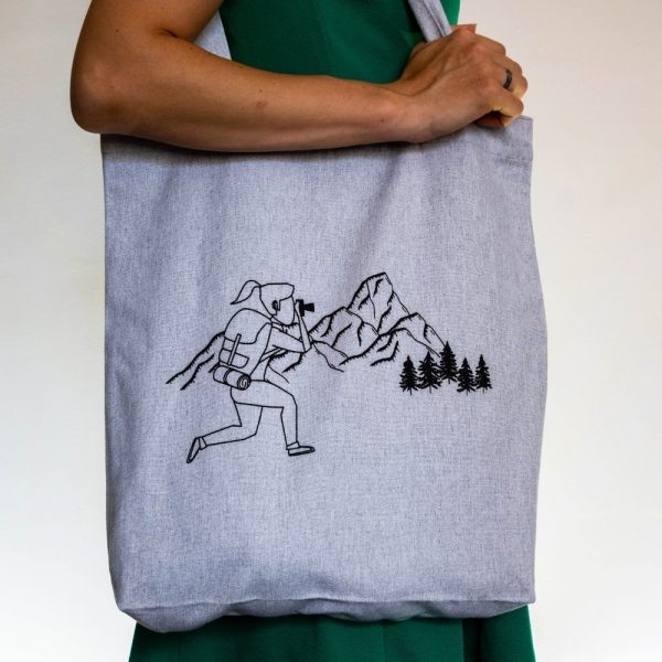 Eco-friendly reusable tote bag made from 80% recycled cotton and 20% recycled polyester. Light gray with a black mountain photography print.
