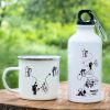 White enamel mug and 400ml aluminum bottle with a minimalist adventure-themed design, placed on a wooden surface with a green nature background.