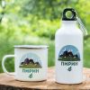 podarak-komplekt-butilka-kanche-pirin White enamel mug and 400ml aluminum bottle with a mountain-inspired design of Pirin, placed on a wooden surface with a green nature background.
