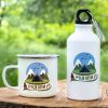 podarak-komplekt-butilka-kanche-rodopi White enamel mug and 400ml aluminum bottle with a scenic Rhodope Mountains design, placed on a wooden surface with a green nature background.