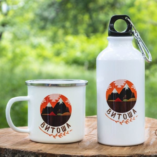 podarak-komplekt-butilka-kanche-vitosha White enamel mug and 400ml aluminum bottle with a colorful mountain design representing Vitosha, placed on a wooden surface with a green nature background.