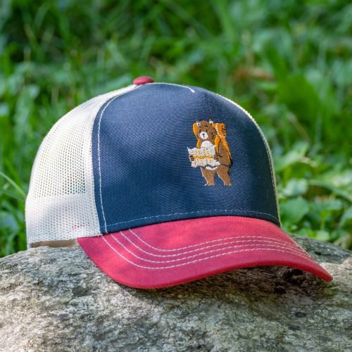 shapka-s-kozirka-i-mrezha-bordo-mecho-turist Trucker cap with embroidered hiking bear design, featuring a navy blue front, red visor, and breathable mesh back.