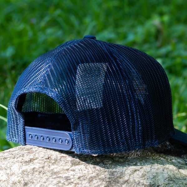 Back view of a navy blue mesh cap with an adjustable snap closure, placed on a rock.