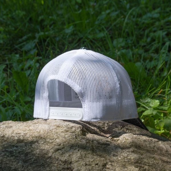 Back view of a white mesh trucker cap with adjustable snap closure, placed on a rock outdoors.
