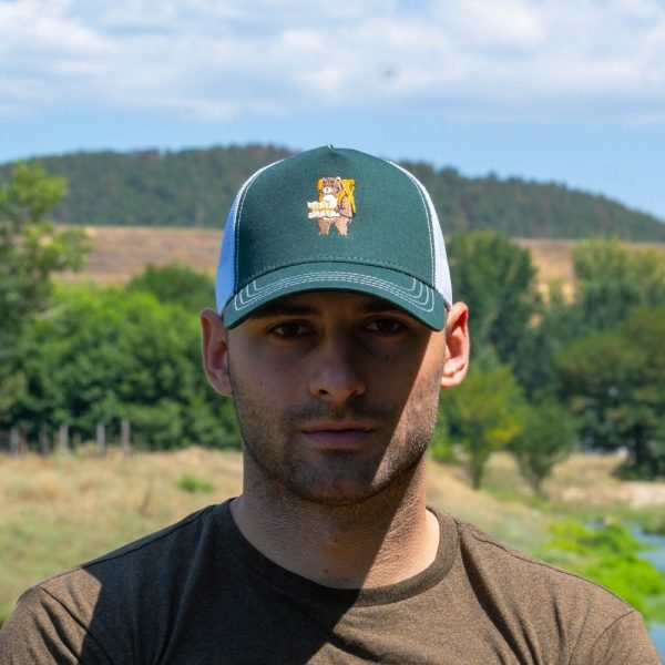 Man wearing a green mesh-back cap with an embroidered bear carrying a backpack and map.