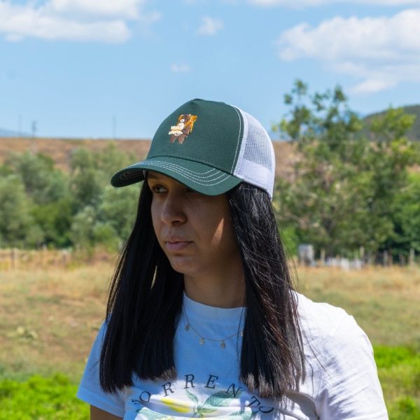 Woman wearing a green mesh-back cap with an embroidered bear carrying a backpack and map.