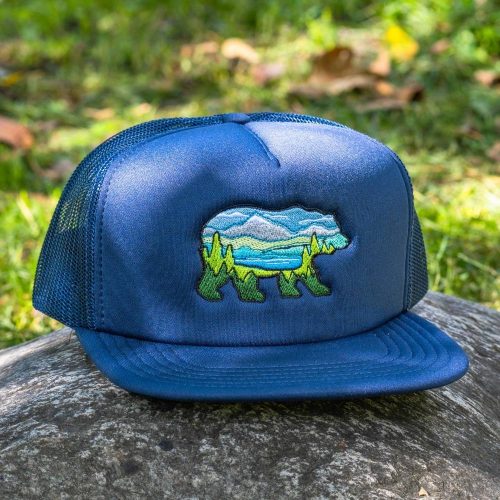Navy blue mesh trucker hat with a flat brim and embroidered bear landscape design.