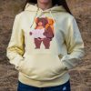swearshirt-hoodie-zhylto-turist Yellow hoodie with a hiking bear illustration, worn by a woman outdoors.