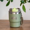 thermo-chasha-za-kafe-chai-fotoaparat Green stainless steel thermal mug (350 ml) with a laser-engraved camera and nature design. The lid is closed, featuring a green locking mechanism, and a carrying strap is attached to the side.