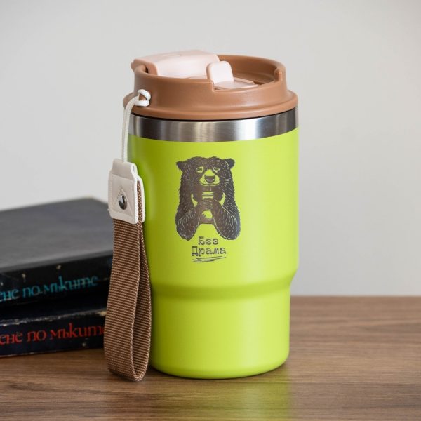 Green stainless steel thermal mug with an engraved illustration of a bear holding a cup. Features a durable design, a dual lid with a straw and classic drinking spout, and a carrying strap.