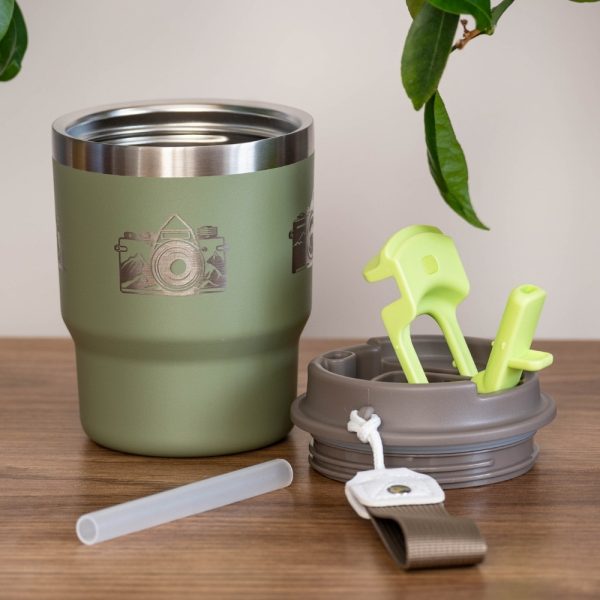 thermo-chasha-za-kafe-chai-metalna Green stainless steel thermal mug (350 ml) with a laser-engraved camera and mountain design. The lid and straw are placed beside it.