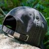 Back view of a vintage black baseball cap with an adjustable metal strap.