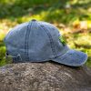 Side view of a vintage blue baseball cap with an embroidered bear and mountain landscape, featuring an adjustable metal buckle.