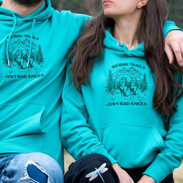 unisex-hoodie-sweatshirt-zelen-mechki turquoise hiking hoodie with quote “No bad trails just bad knees” and mountain hiker illustration, unisex model