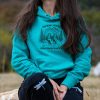zhensko-hoodie-s-kachulka turquoise women's hoodie with quote “No bad trails just bad knees” and mountain hikers illustration, worn outdoors