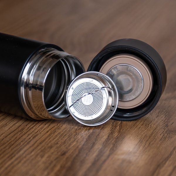 cheren-termos-za-chai Close-up of stainless steel tea infuser and thermos lid next to an open black thermos.