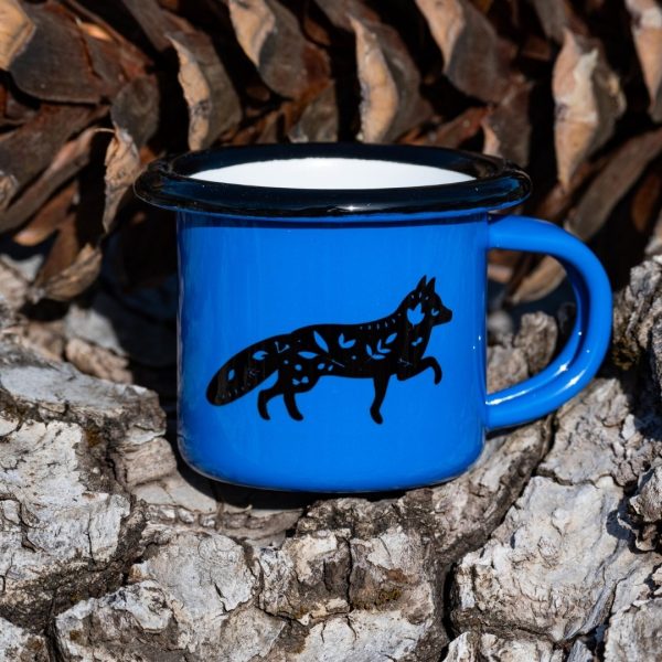 mini-kenche-metalno Small blue enamel mug with black running fox illustration, placed outdoors on bark.