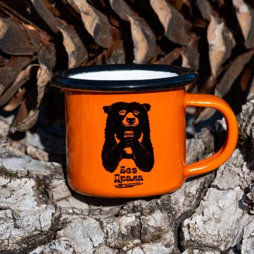 oranzhevo-kanche-mini Small orange enamel mug with black bear illustration and text “No Drama”, placed on bark outdoors.