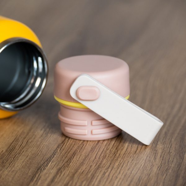 Close-up of pastel pink thermos lid with white foldable handle.