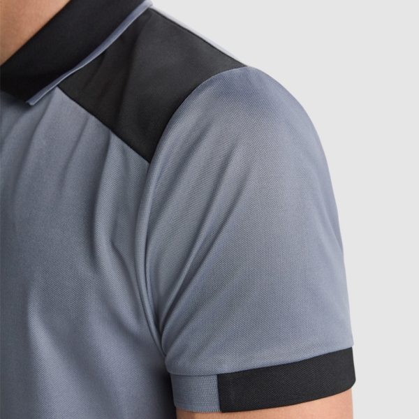 Close-up detail of gray and black polyester polo shirt sleeve and shoulder panel showing textured performance fabric and contrasting design elements