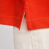 Close-up detail of the side slit on a premium red cotton polo shirt made from heavyweight 230 gsm fabric with reinforced stitching