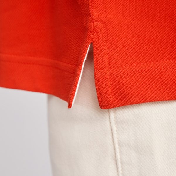 Close-up detail of the side slit on a premium red cotton polo shirt made from heavyweight 230 gsm fabric with reinforced stitching